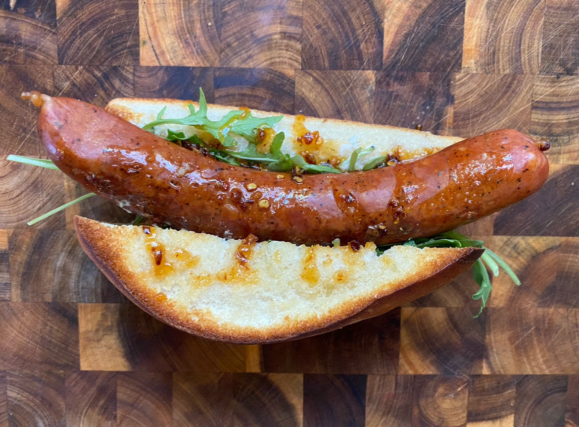 Pork and beef sausage with hot honey, herb goat cheese spread, and arugula